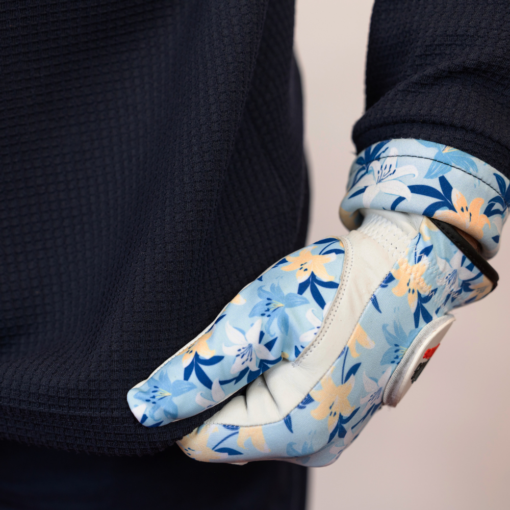 Gloves with a blue floral pattern worn by a person in a dark sweater.