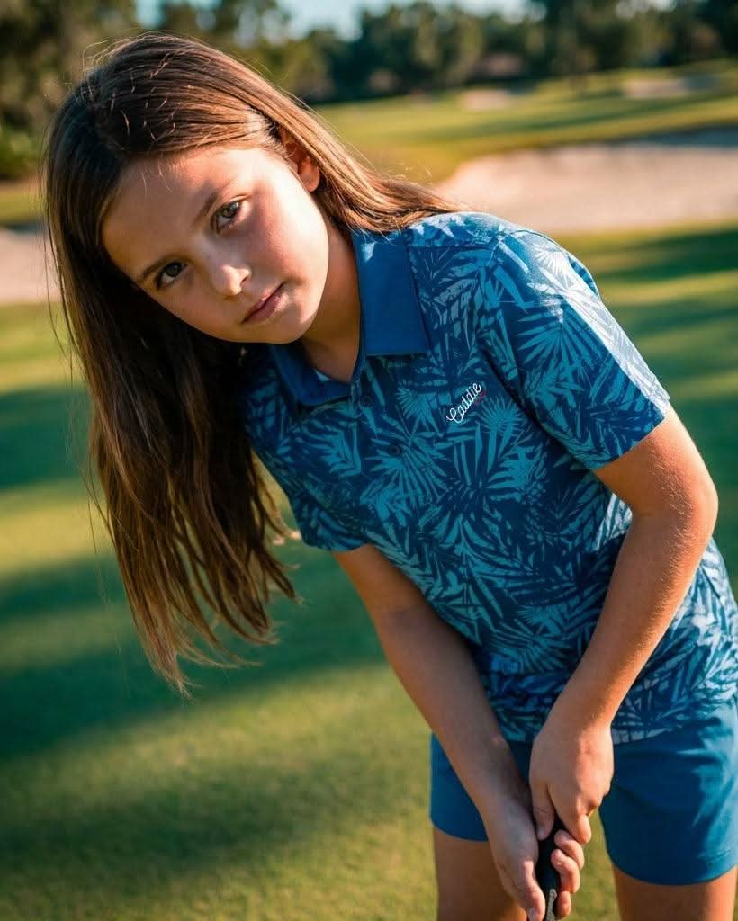 Young girl in a blue patterned outfit standing on a golf course