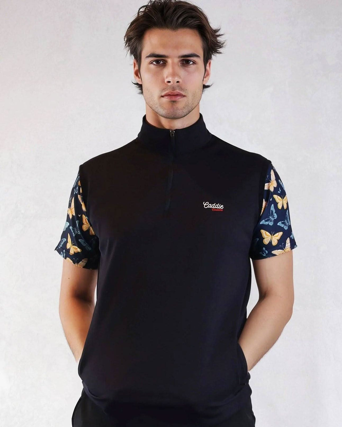 Man wearing a black quarter-zip shirt with butterfly pattern sleeves on a white background