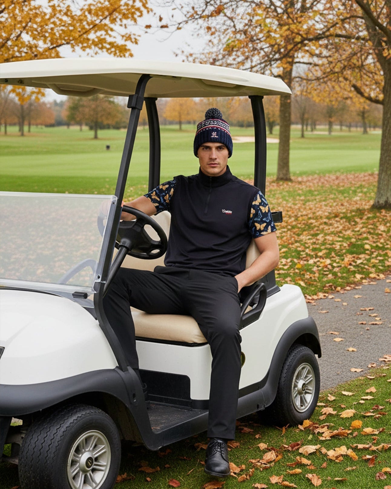 Man sitting in a golf cart on a golf course with autumn leaves and trees in the background