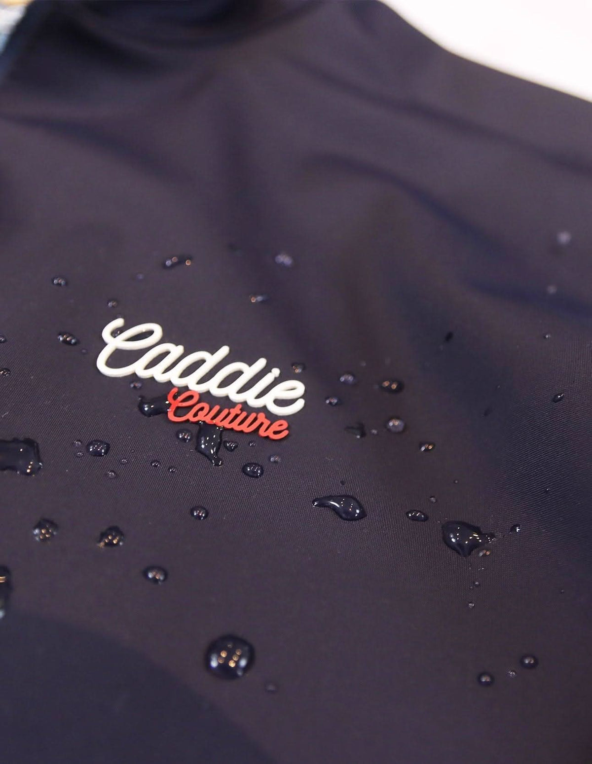 Navy Golf Vest with 'Caddie Couture' logo on a white background. with Droplets of water on