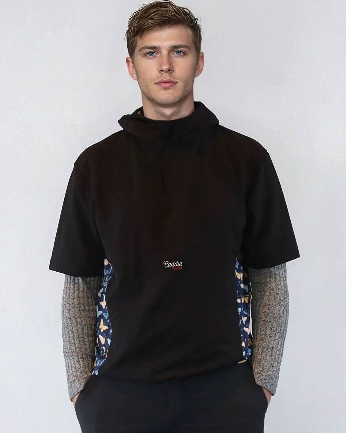 Man wearing a black windbreaker shirt with patterned sides against a white background