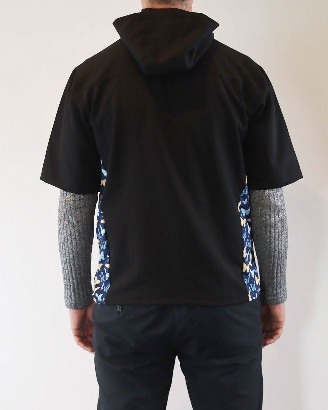 Person wearing a black windbreaker shirt with floral sides against a plain background