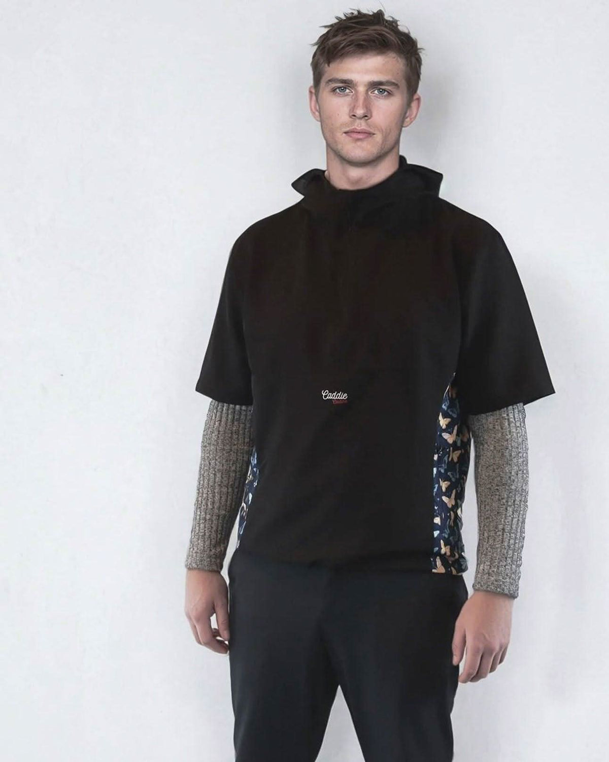 Man wearing a black windbreaker shirt with patterned sides on a white background