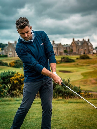 man wearing blue hoodie swinging golf club