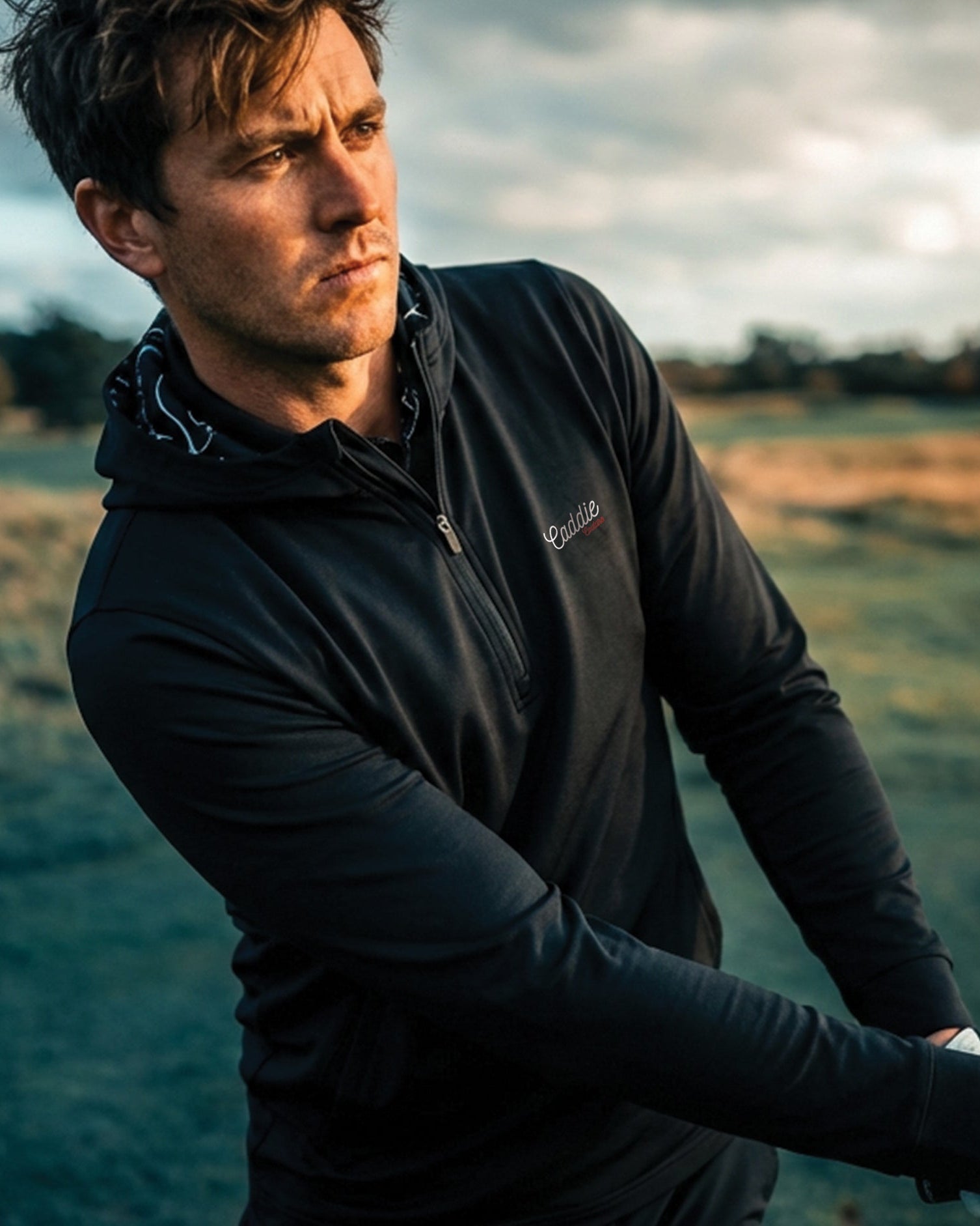 man wearing blue hoodie swinging golf club