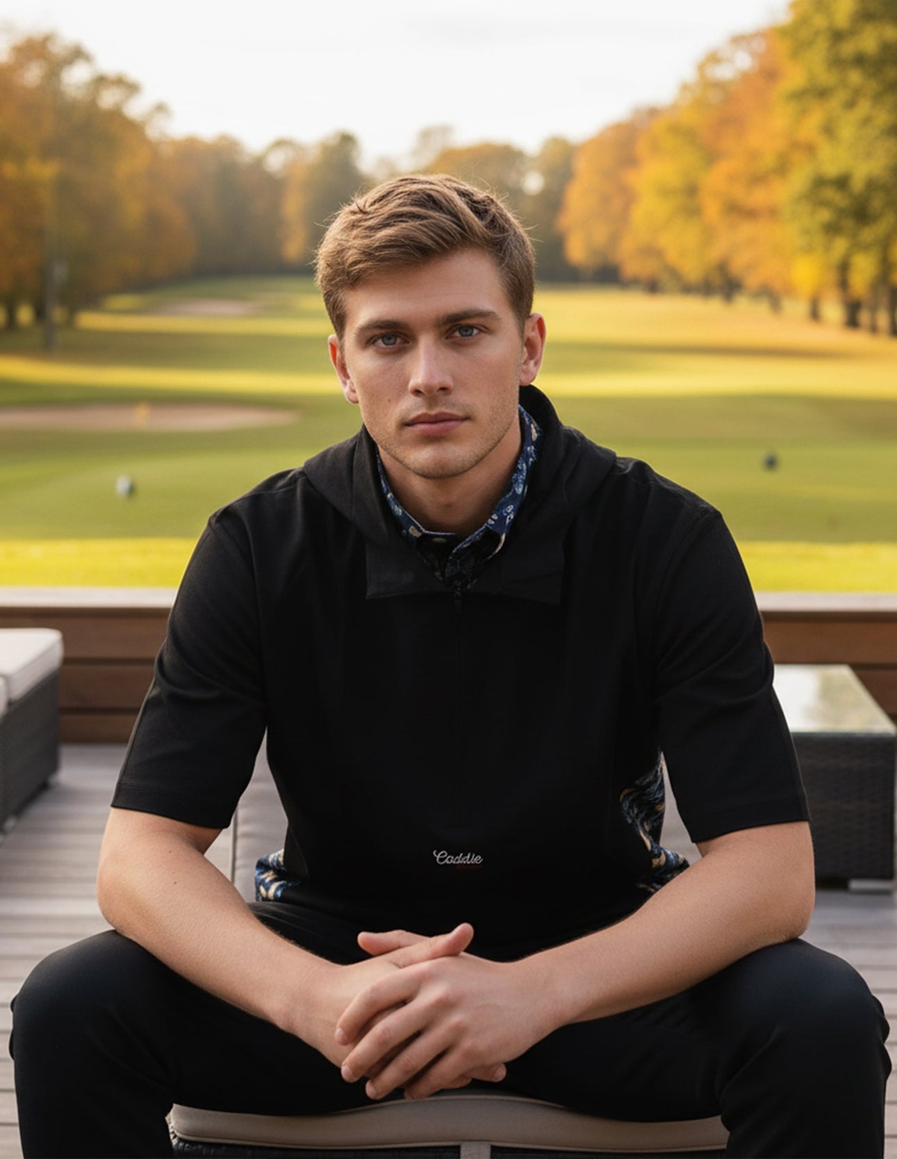 man wearing windbreaker shirt sitting on a bench at a golf course