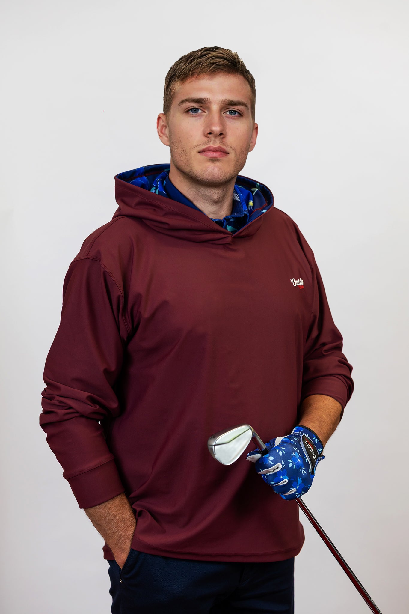Man wearing a maroon hoodie with a blue inner lining, holding a golf club.