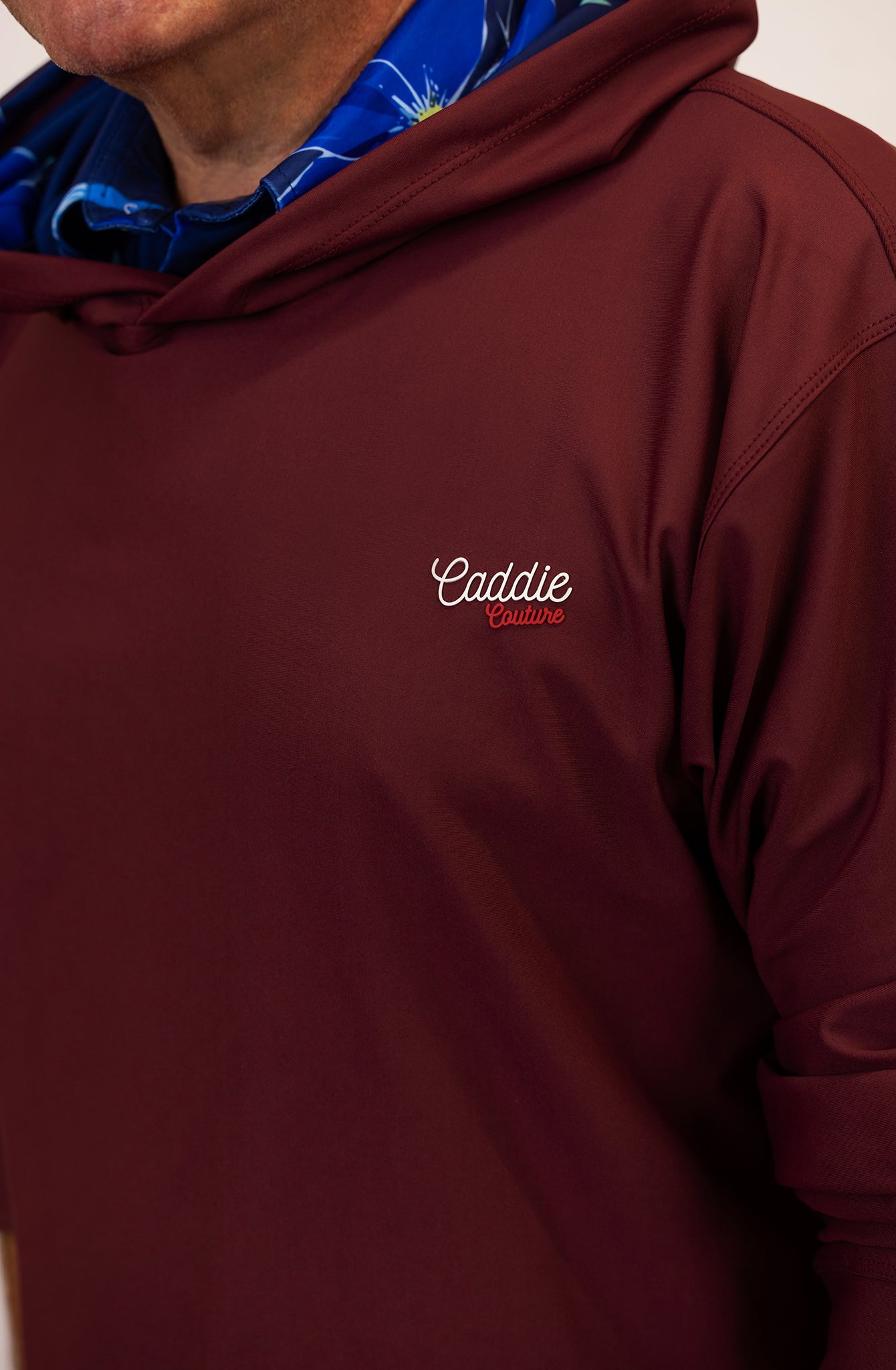 Maroon golf hoodie with 'Caddie' logo on a neutral background
