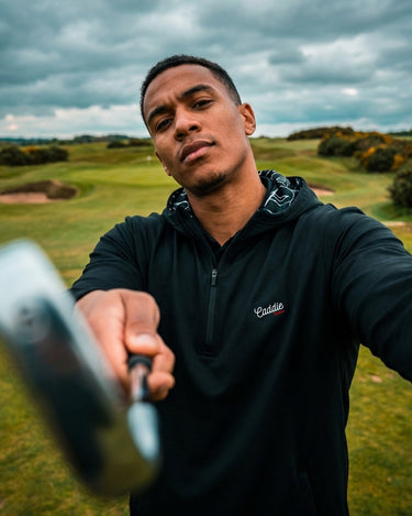 Man holding a golf club on a golf course with a cloudy sky