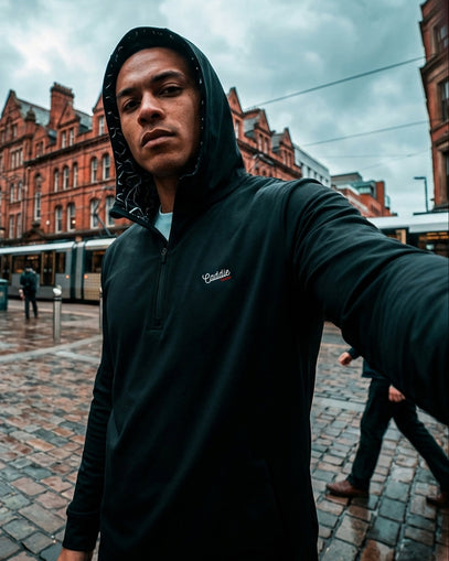 Man taking a selfie on a city street with brick buildings in the background