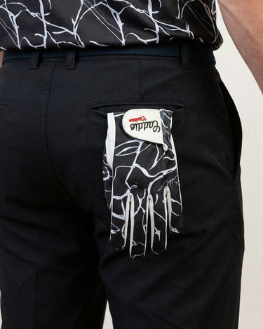 Person wearing black pants with a patterned golf glove hanging out the back pocket