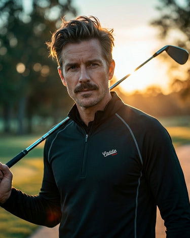 Man holding a golf club on a golf course with sunset in the background