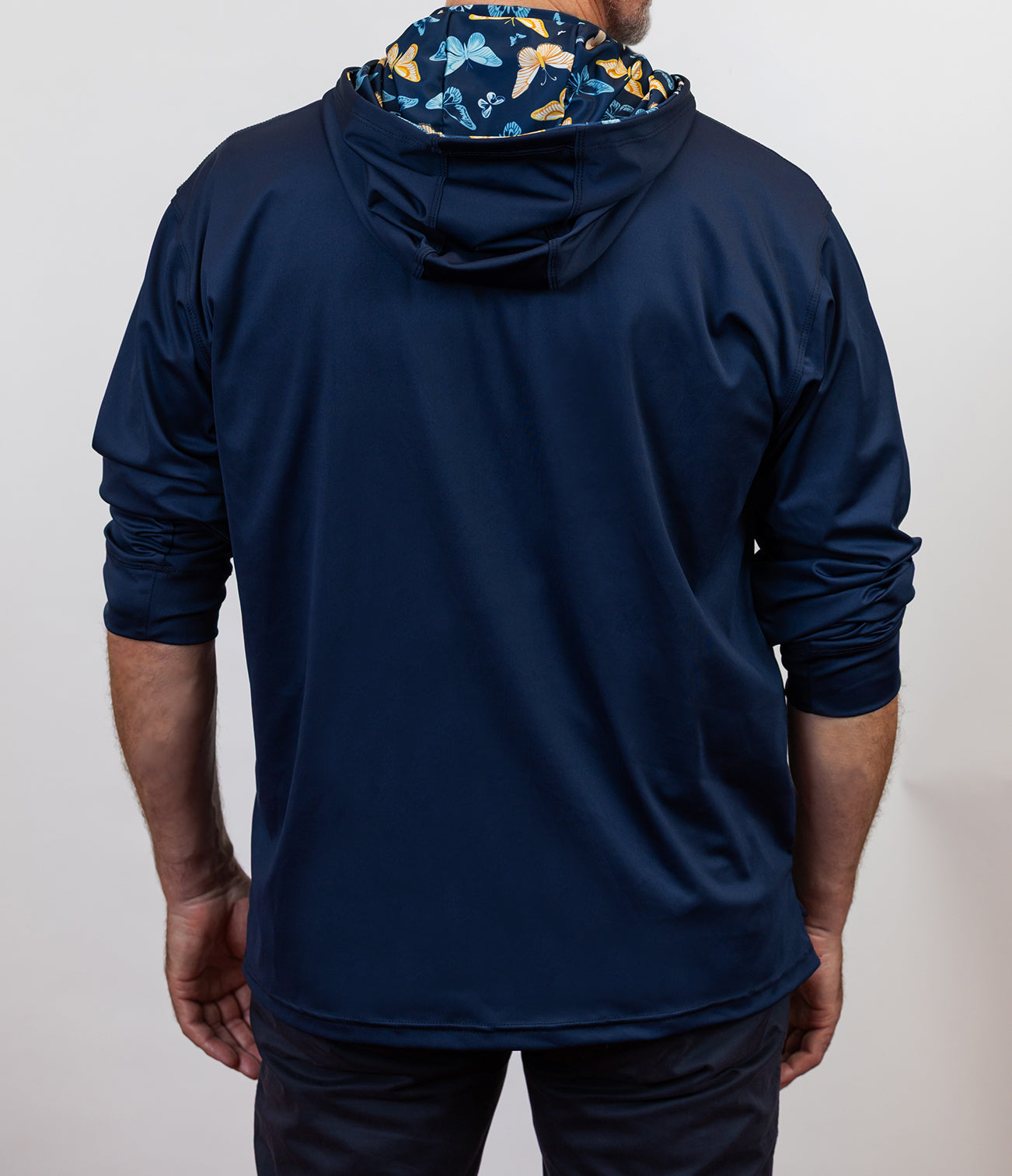 Person wearing a navy blue hoodie with a butterfly pattern on the hood against a white background