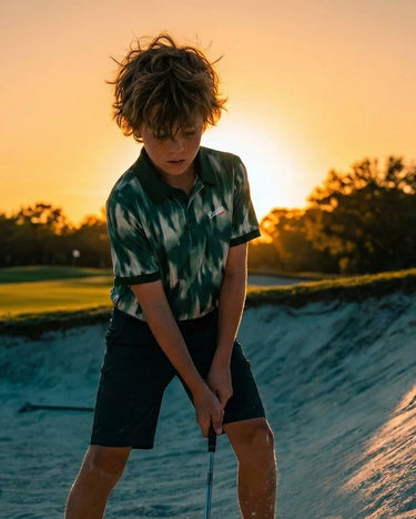 Child playing golf on a sand trap with sunset in the background