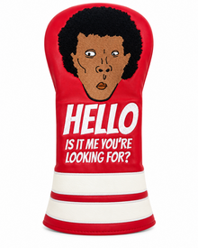A red golf club headcover featuring a graphic of a Lionel Ritchie with an afro and the text 'HELLO IS IT ME YOU'RE LOOKING FOR?' in white, with white horizontal stripes at the bottom.