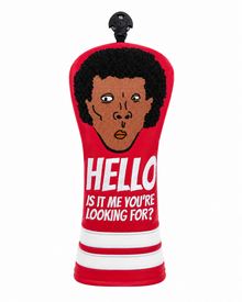 A red golf club headcover with a cartoon face of a man with black hair and the text 'HELLO IS IT ME YOU'RE LOOKING FOR?' in white, on a white background.