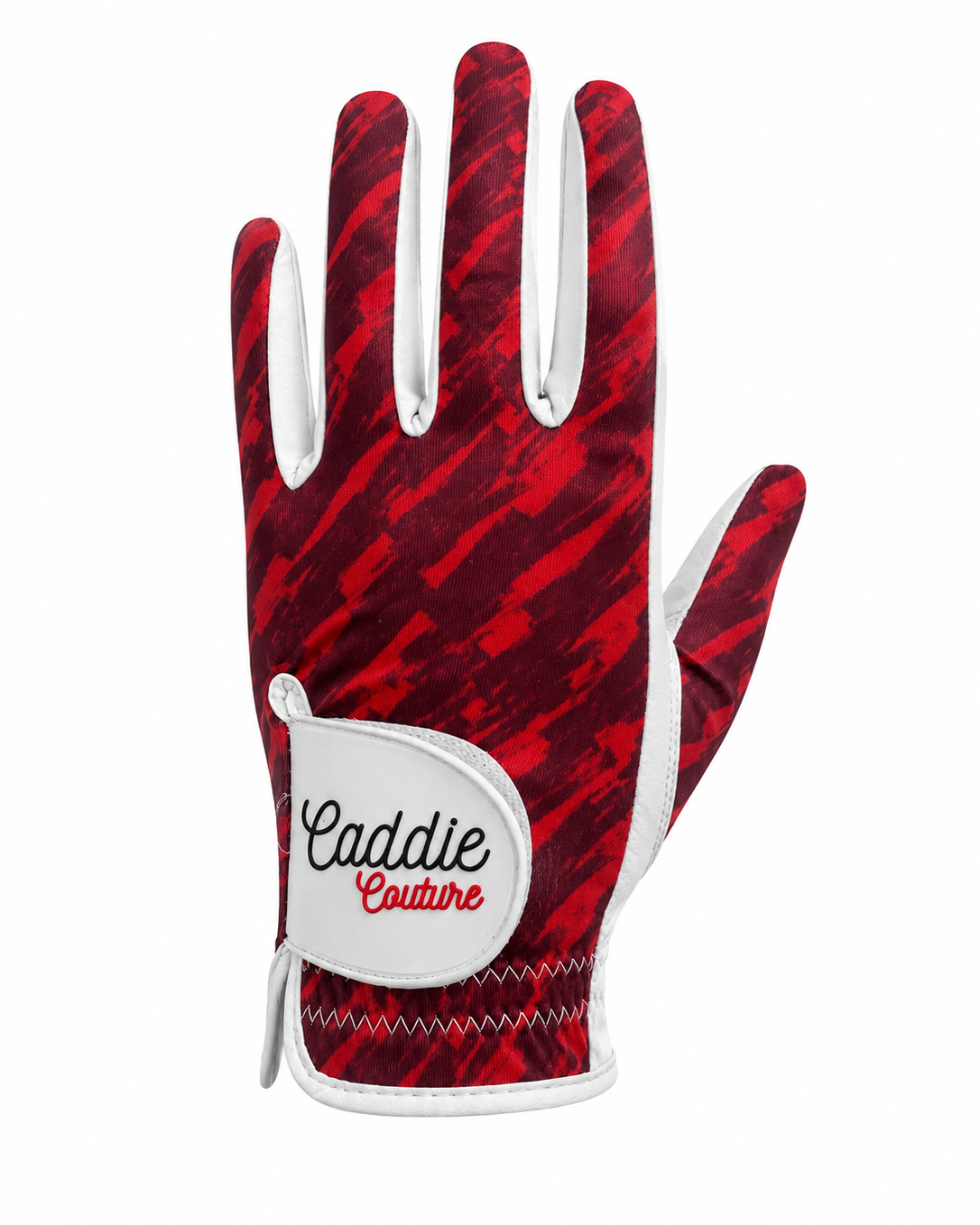 A single golf glove from Caddie Couture featuring a red and black abstract patterned back with white trim and a white wrist patch displaying the brand name.