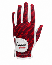 A single golf glove from Caddie Couture featuring a red and black abstract patterned back with white trim and a white wrist patch displaying the brand name.