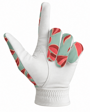 A white leather golf glove with a coral red and mint green abstract pattern on the back of the hand and along the wrist strap, shown against a plain white background.