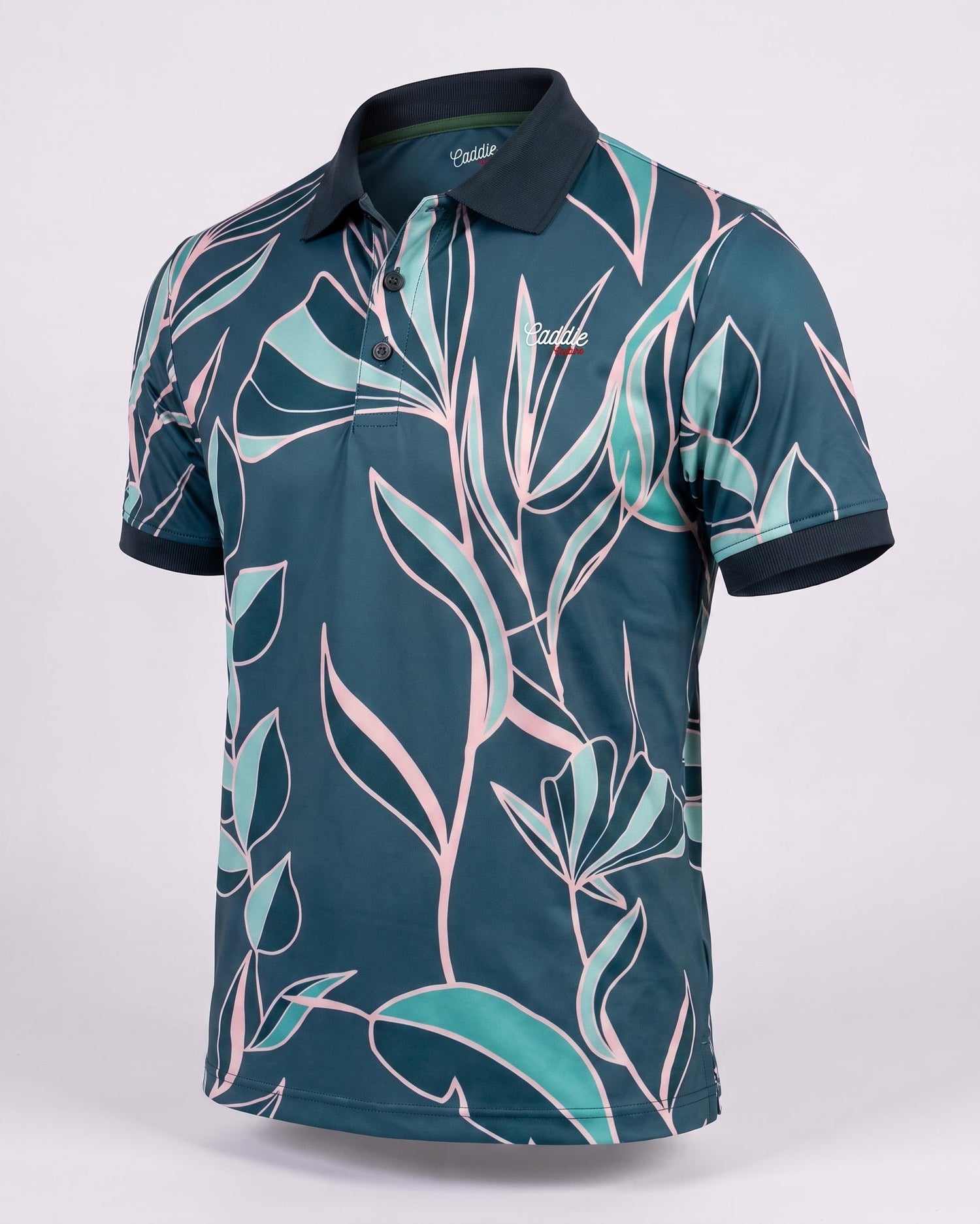 A short-sleeve golf polo shirt with a dark teal base and a tropical leaf pattern in light teal and pink, featuring a dark navy collar and sleeve cuffs, displayed on a light gray background.