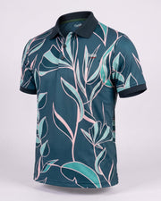 A short-sleeve golf polo shirt with a dark teal base and a tropical leaf pattern in light teal and pink, featuring a dark navy collar and sleeve cuffs, displayed on a light gray background.