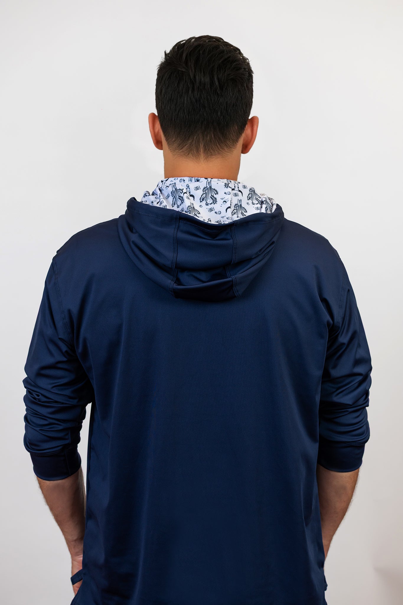 Person wearing a navy blue golf hoodie with a pattern inside on a white background