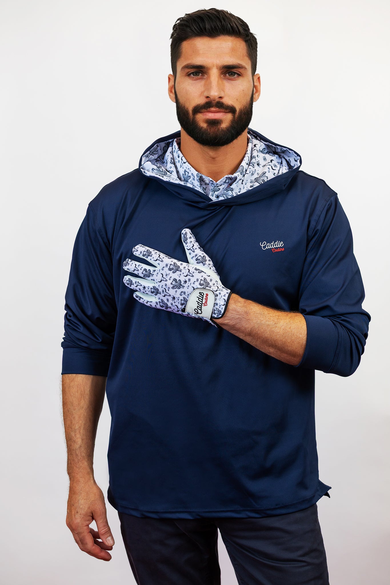 Man wearing a navy blue golf hoodie with floral patterns on a white background
