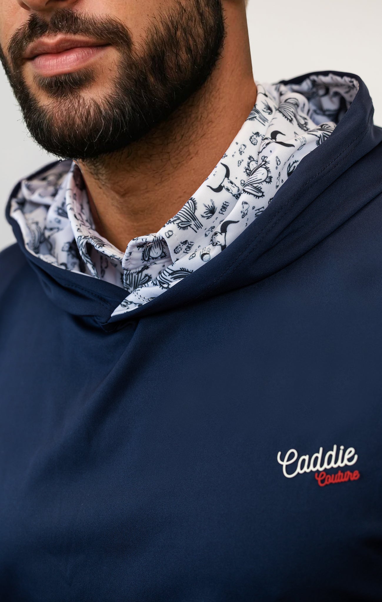 Man wearing a navy blue hoodie with a patterned collar and 'Caddie Couture' branding.