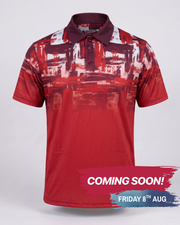 A short-sleeve polo shirt with a red, white, and dark maroon abstract brushstroke pattern, shown on a light gray background with a 'COMING SOON!' promotional banner at the bottom.