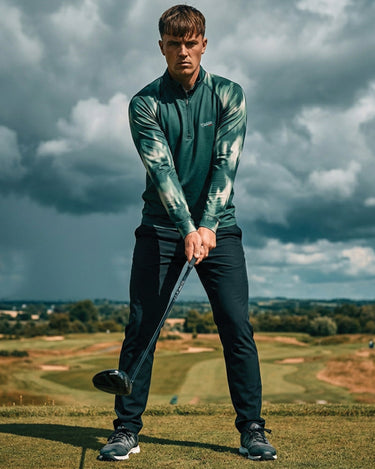 Man playing golf on a cloudy day with a scenic background