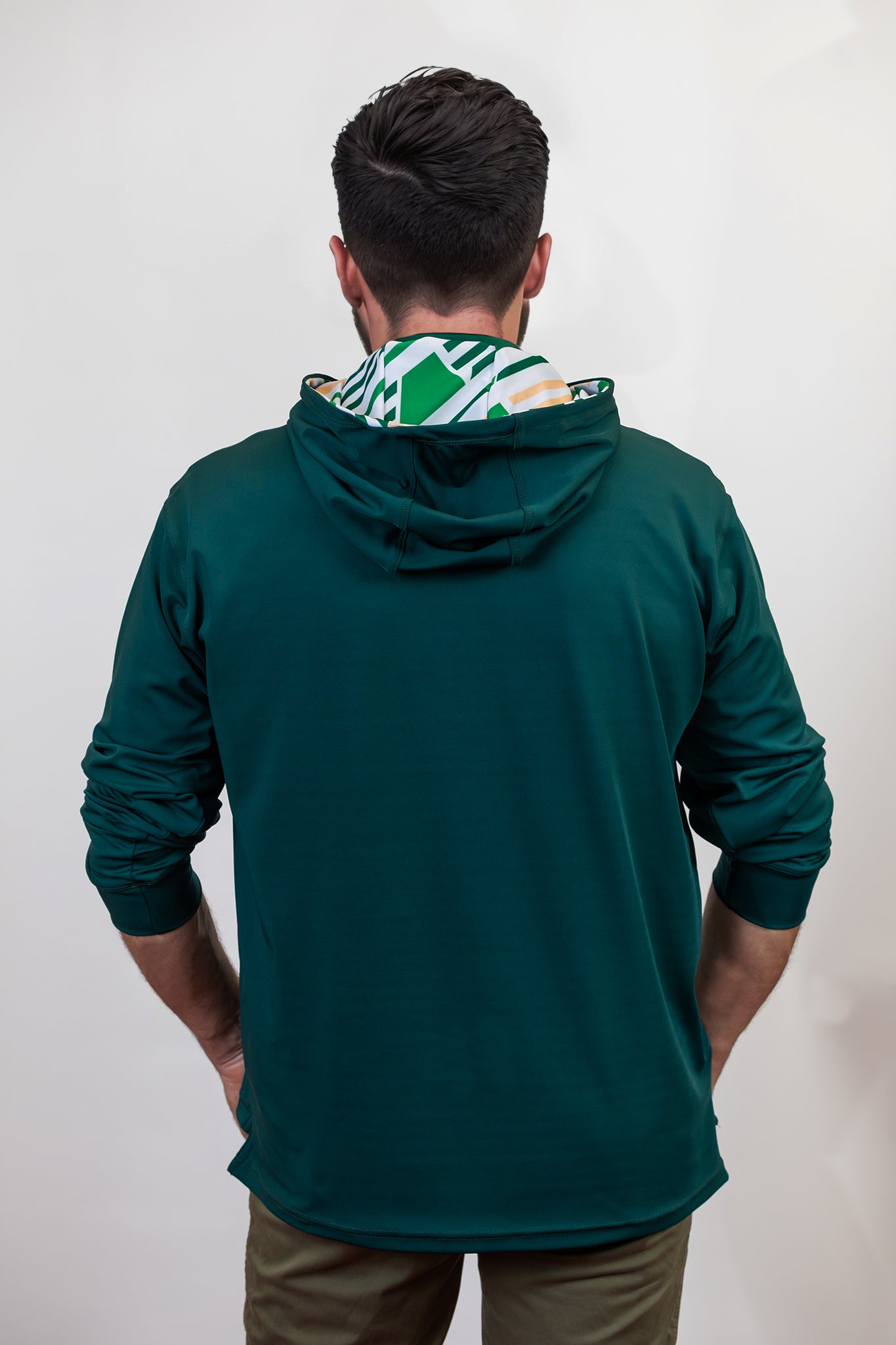 Person wearing a green golf hoodie with a patterned hood against a white background