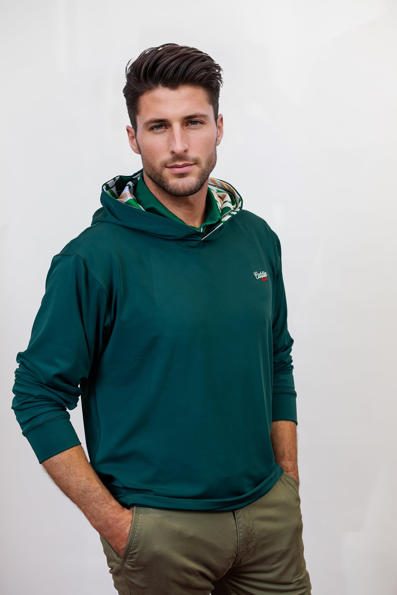 Man wearing a green golf hoodie with a patterned hood against a white background