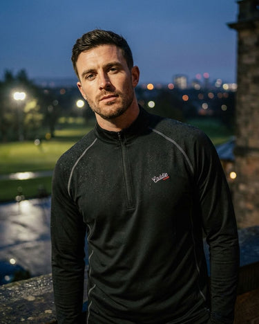 Man wearing a black jacket with a brand logo on a golf course at night.