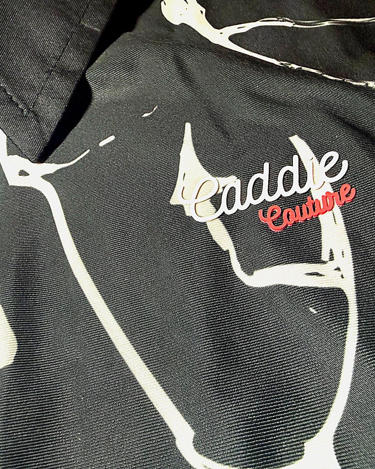 Close-up of a GOLF POLO with 'Caddie Couture' branding on a camouflage pattern.