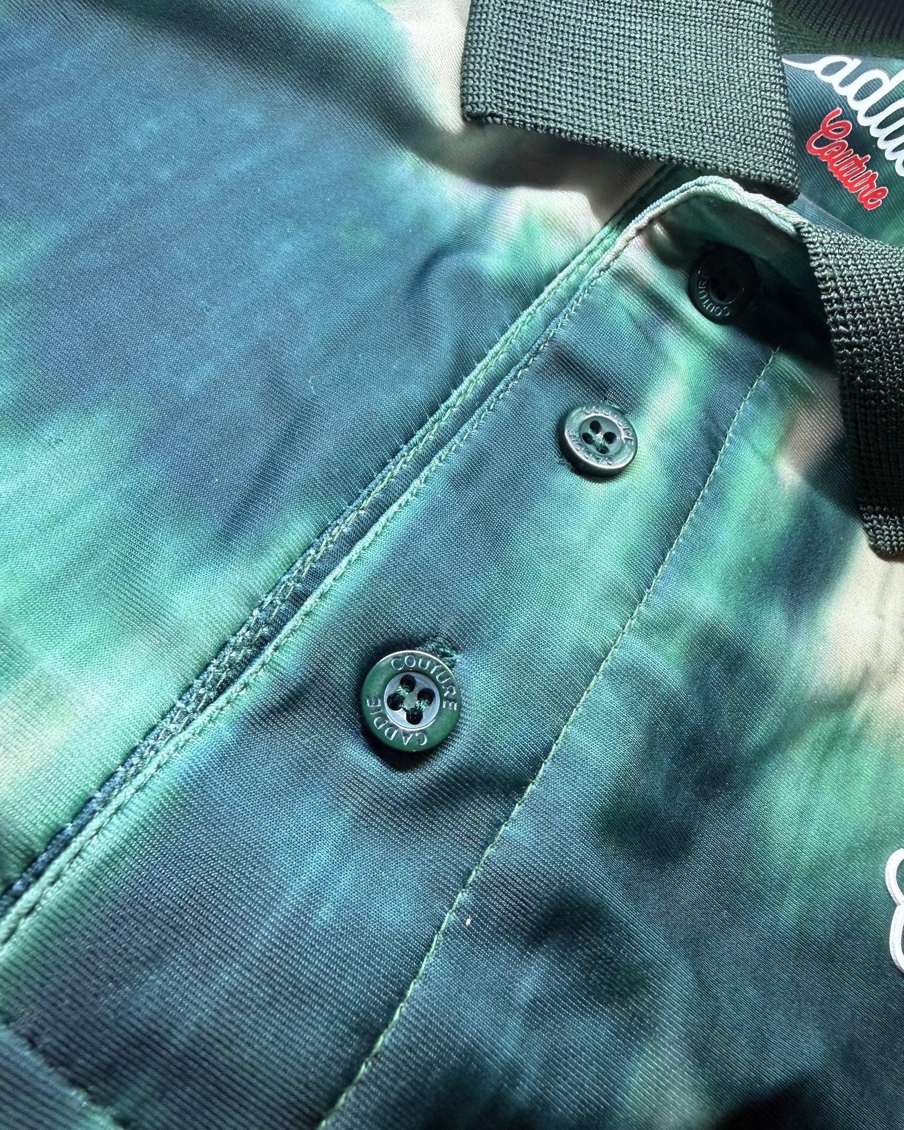 Close-up of a green camouflage-patterned bag with a button and brand logo.