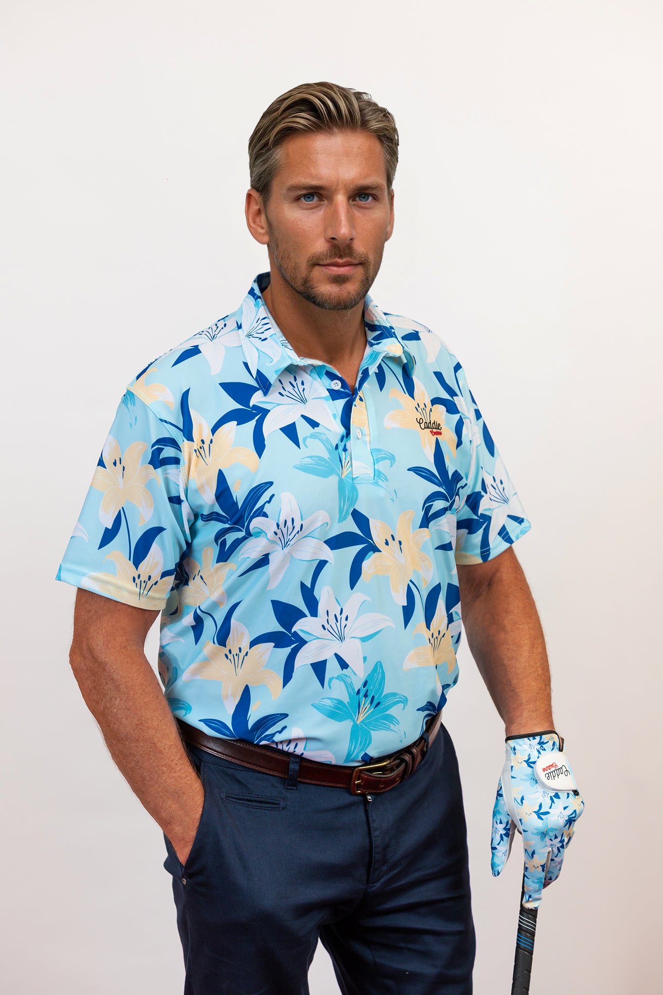Man wearing a blue floral golf shirt and dark pants, holding a golf club.