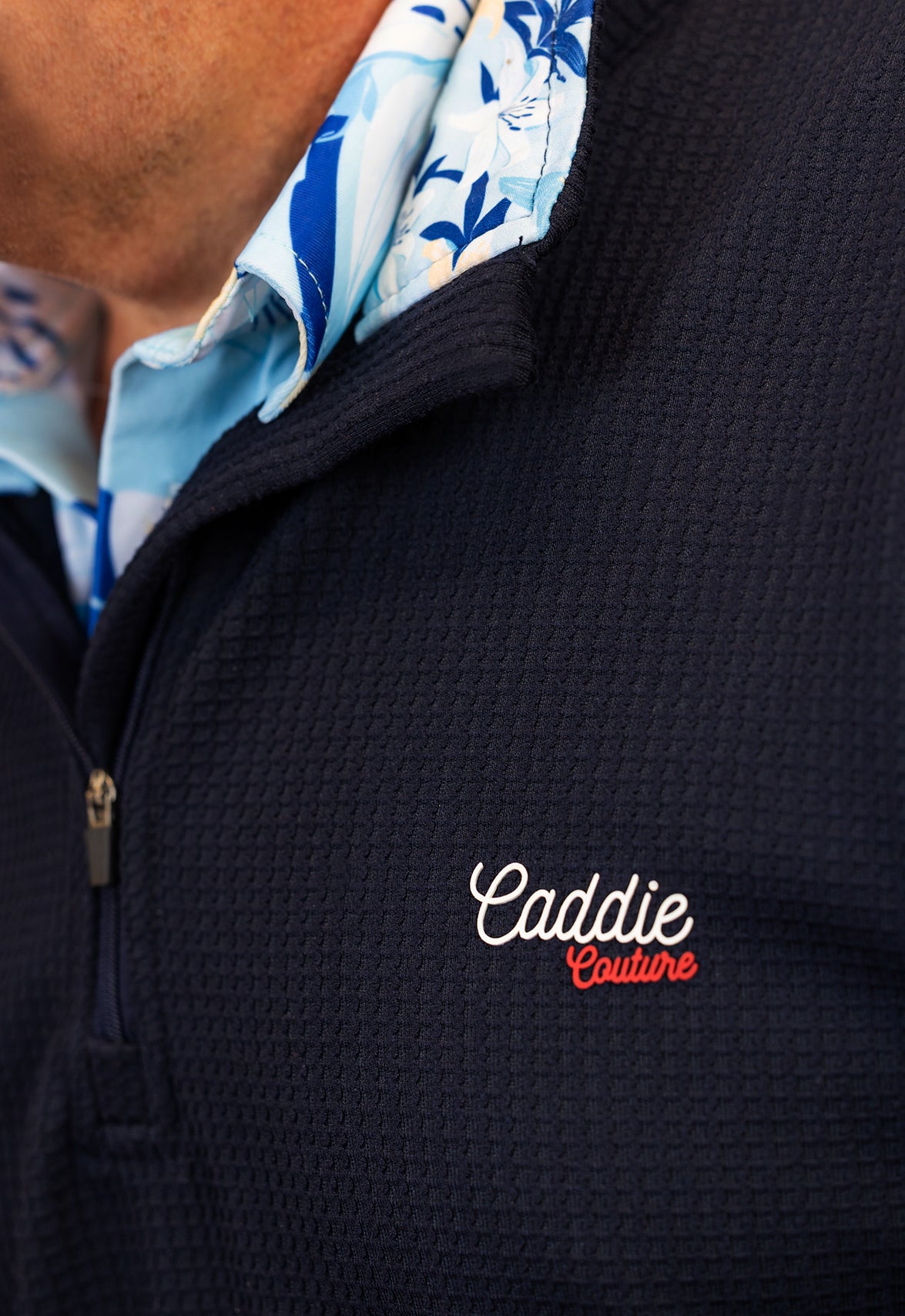 Navy blue jacket with 'Caddie Couture' logo, featuring a floral patterned shirt underneath.