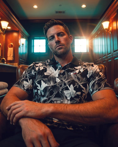 Man sitting in a luxurious interior setting wearing a floral shirt.