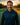 Man in a navy blue jacket with a logo on a golf course at sunset