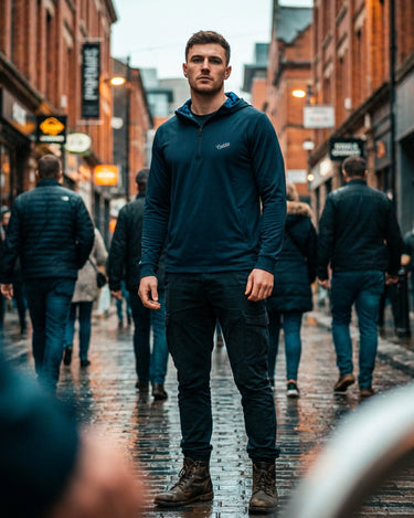 Man in a blue hoodie walking through a busy city street.