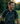 Man laughing outdoors with a blurred natural background