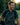 Man laughing outdoors with a blurred natural background