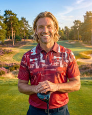 A smiling man with blonde hair stands on a golf course wearing a red and white patterned polo shirt, holding a golf club. Trees, grass, and sand bunkers are visible in the background during golden hour.