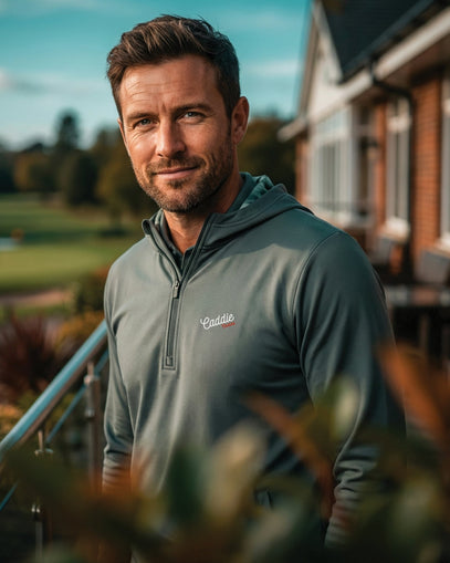 Man wearing a branded jacket standing outdoors with a golf course in the background