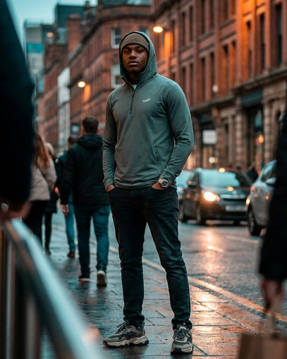 Man in a green hoodie standing on a city street at night