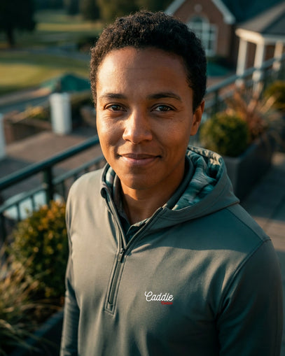 Person wearing a green jacket with a brand logo on a balcony with plants and a house in the background