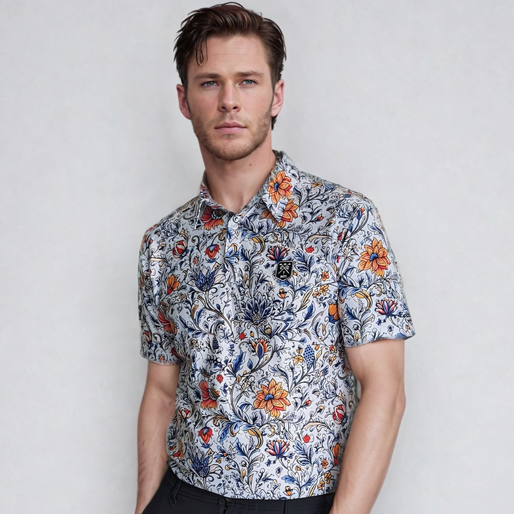 A man wearing a white short-sleeved golf polo with a vintage floral design in blue, orange, and green colors.