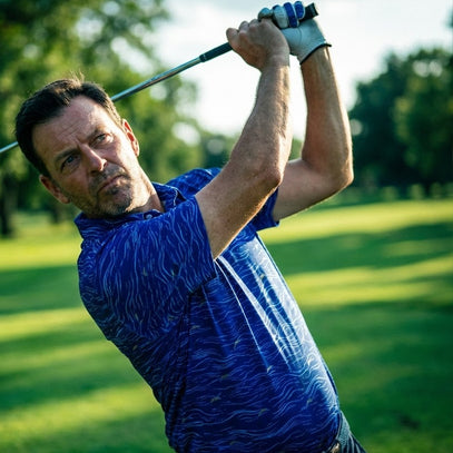 man swinging golf club wearing blue waves golf polo