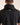 Person wearing a black shirt with 'Caddie' branding on the back against a beige background